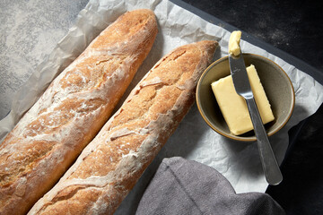 food, baking and cooking concept - close up of bread, butter in bowl and table knife on towel