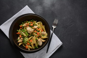 Pasta salad with baked vegetables and fried pieces of chicken breast . Penne pasta with broccoli, beans and carrots.