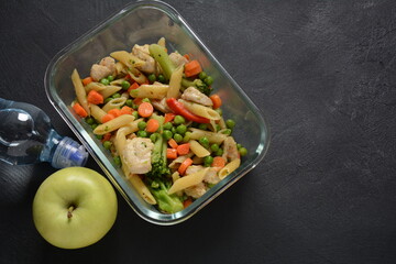 Lunch box with pasta salad, baked vegetables and fried pieces of chicken breast . Healthy lunch concept.