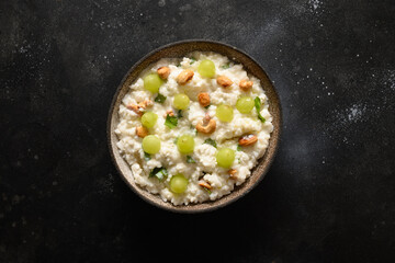 Curd Rice with cashews, grapes, cilantro, ginger on a black background. Indian South cuisine. View from above.