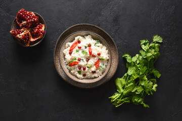 Curd Rice with pomegranate, cilantro, mustard seeds, ginger on a black background. Indian South cuisine