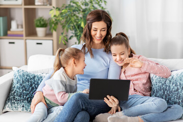 people, family and technology concept - happy mother and two daughters with tablet pc computer having video call at home