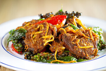 Crispy fried Catfish with curry paste in white dish on brown wooden table. Thai food