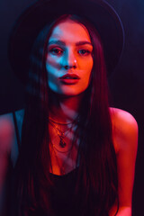 Portrait of beautiful girl in a hat with a red blue neon light