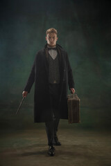 Young man in art action isolated on dark green background. Retro style, comparison of eras concept.