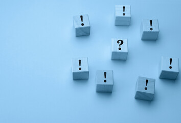 wooden cubes with exclamation marks and a question mark in the middle on a light blue background