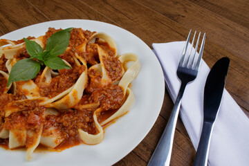 Tagliatelle pasta with bolognese sauce and basil leaves. Close-up photograph of handmade pasta....