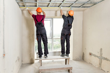 Installation of drywall. Workers are measuring. - obrazy, fototapety, plakaty