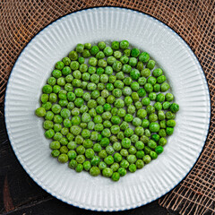 Tasty green peas in a white plate. Top view. 