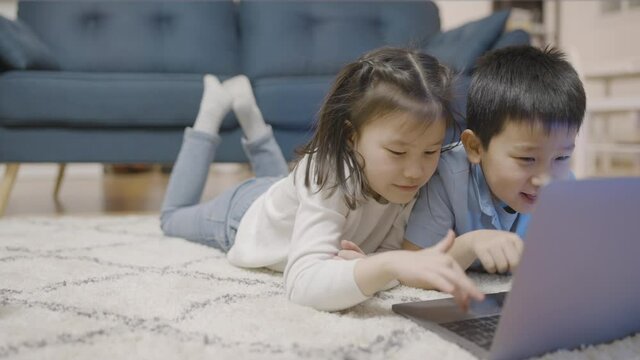 Adorable asian kids using laptop, browsing internet together, computer literacy