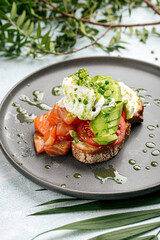 Appetizing avocado sandwich with salmon and poached egg for breakfast