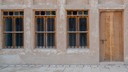 Front view of an Arabic old wall with traditional wooden windows and door in Qatar.