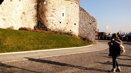 Entrance to the castle. Couple walking on the street. Scenic view of the old town country on a sunny day. Beautiful scape with medieval castle. Group of young people sightseeing famous Krakow landmark