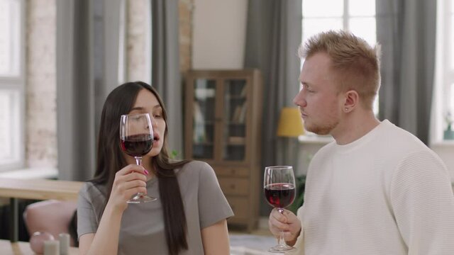 Medium Shot Of Happy Young Man And Woman Enjoying Red Wine And Dancing Together At Home While Celebrating Something