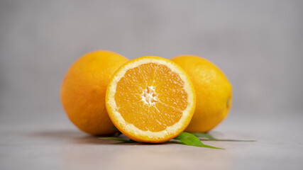 Two Orange fruit with one sliced orange on a gray background. Orange fruit