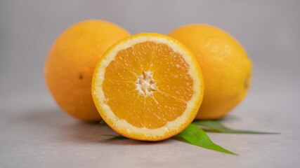 Two Orange fruit with one sliced orange on a gray background. Orange fruit