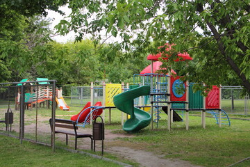 Modern Russian plastic outdoor children play ground on green trees background at summer day, kids vacation on the city yard in Moscow