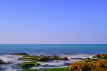 Long exposure by the sea. Waves break against stones.