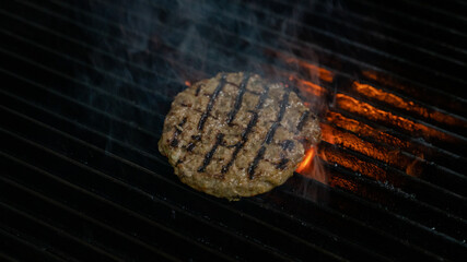 cooking burgers patty on hot grill with flames. Burger preparation