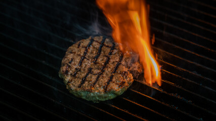 cooking burgers patty on hot grill with flames. Burger preparation