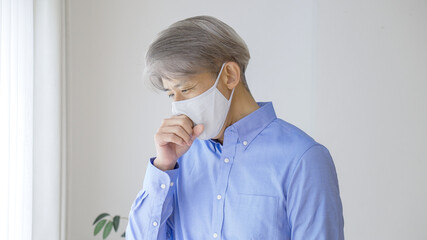 マスクをしながら咳をするシニア男性