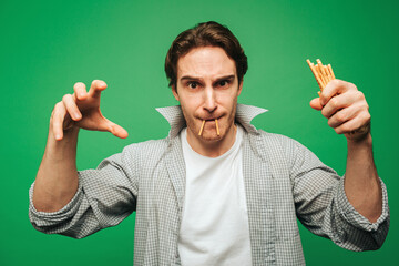 Young man plays with straw pretend being Dracula, isolated on green background