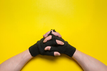 A male hand with a crossed fingers on a yellow flat lay background with copy space.