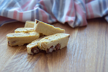 Sweet biscotti cookies with nuts and a striped kitchen towel on wooden background. Side vie