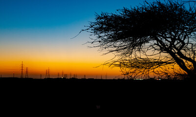 Beautiful sunset in Qatar with high voltage power line towers in the background.