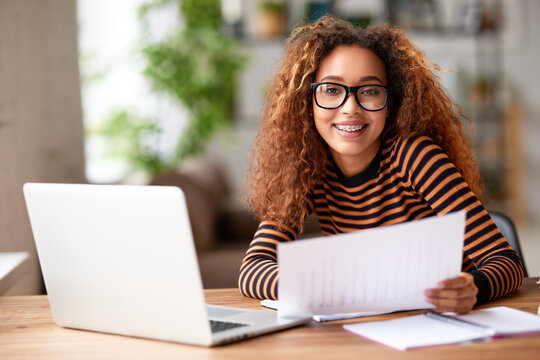 Happy young african american woman smiling at camera while working remotely studying online from home