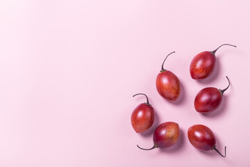 Tamarillo fruit on pink pastel paper background