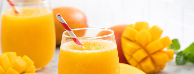 Fresh mango juice smoothie in a glass cup on gray table background.