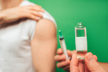 Obraz na płótnie Canvas Close up holding an ampoule before injection, isolated on green background