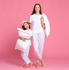 Cheerful mother and daughter with pillows in morning