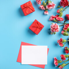 Mother's Day gift. Design concept of holiday greeting card with red carnation bouquet on bright blue table background