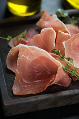 Close-up of jamon or spanish dry-cured ham and fresh thyme, selective focus, vertical shot