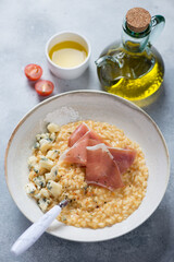 Risotto with pumpkin, prosciutto and gorgonzola, vertical shot on a light-blue stone background