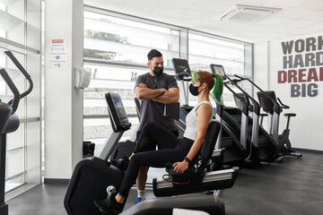 Personal trainer watching sporty woman wearing face masks during pandemic