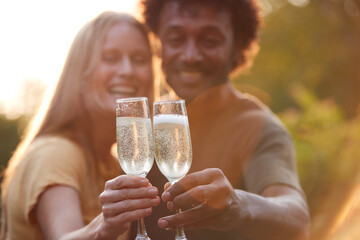 Portrait Of Mature Couple Celebrating Outdoors With Champagne Against Flaring Evening Sun