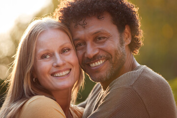 Portrait Of Loving Mature Couple Hugging Outdoors Against Flaring Evening Sun