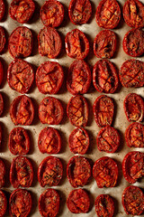 Home cooking sun-dried tomatoes with sea salt and Italian herbs in the oven. Soft selective focus.