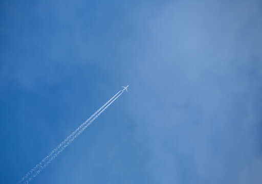 Travel concept image of an airplane flying sky high against blue sky with copy space. 