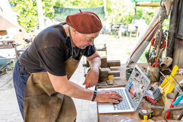 portrait of mature blacksmith. Worker on the computer in the laboratory in the countryside