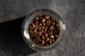Brown coffee grain in a jar on blurred grey background