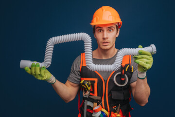 Fototapeta premium Curious builder is having trumpet in arm, isolated over blue background