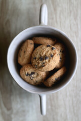 Bowl of chocolate chip cookies on wooden table. Flat lay.