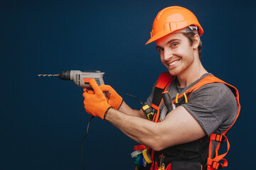 Builder is having equipment in arm and smiling, isolated over blue background