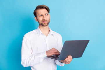 Portrait of attractive minded man holding in hands using laptop overthinking isolated over bright blue color background