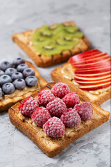 Toasted sandwich bread with peanut butter, frozen berries raspberries, blueberries. Served on concrete background. Healthy, balanced traditional breakfast. Vegan sweet dessert, top view