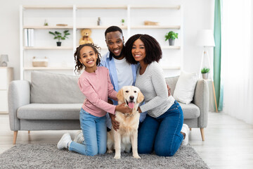 Young black family hugging dog posing at home